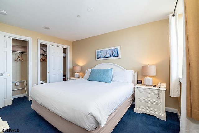 bedroom featuring multiple closets and dark carpet