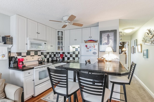 kitchen featuring white appliances, white cabinets, light colored carpet, and tile counters