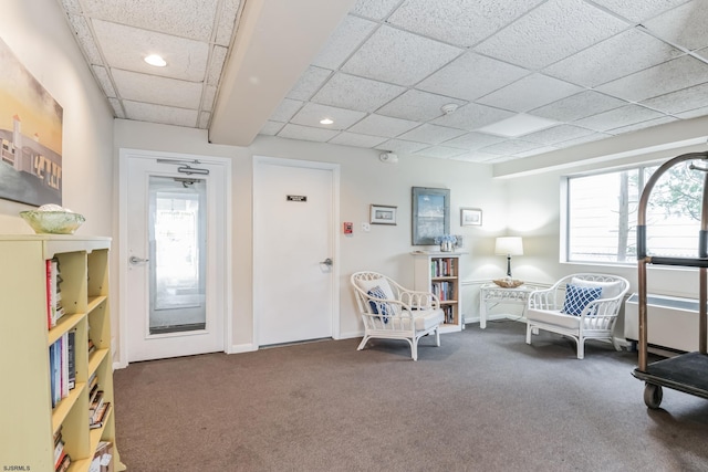 living area with a wealth of natural light, a paneled ceiling, and carpet flooring