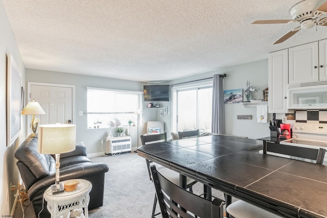 carpeted dining room featuring ceiling fan and a textured ceiling