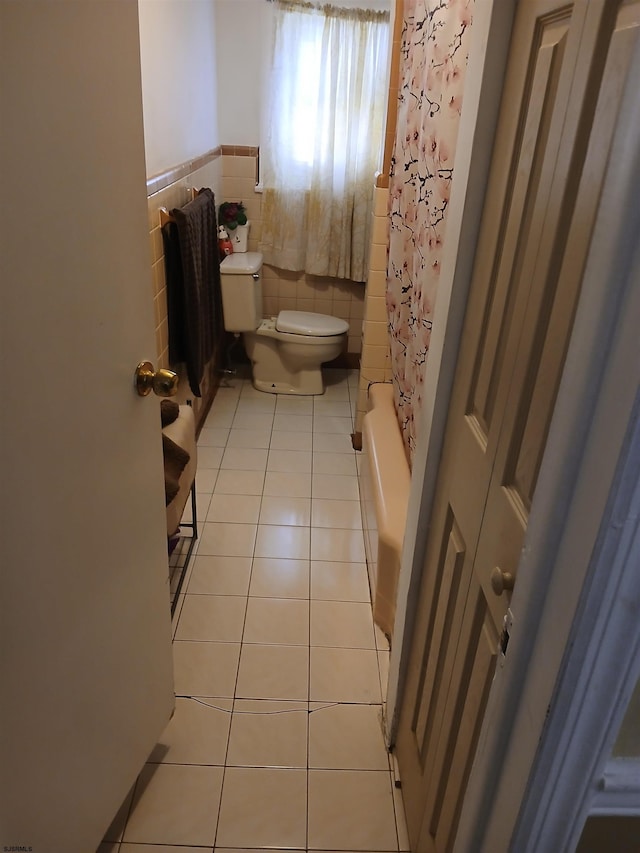 bathroom with tile flooring, shower / tub combo, tile walls, and toilet