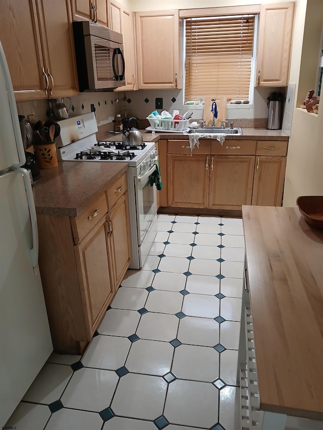 kitchen with sink, white appliances, and light tile floors