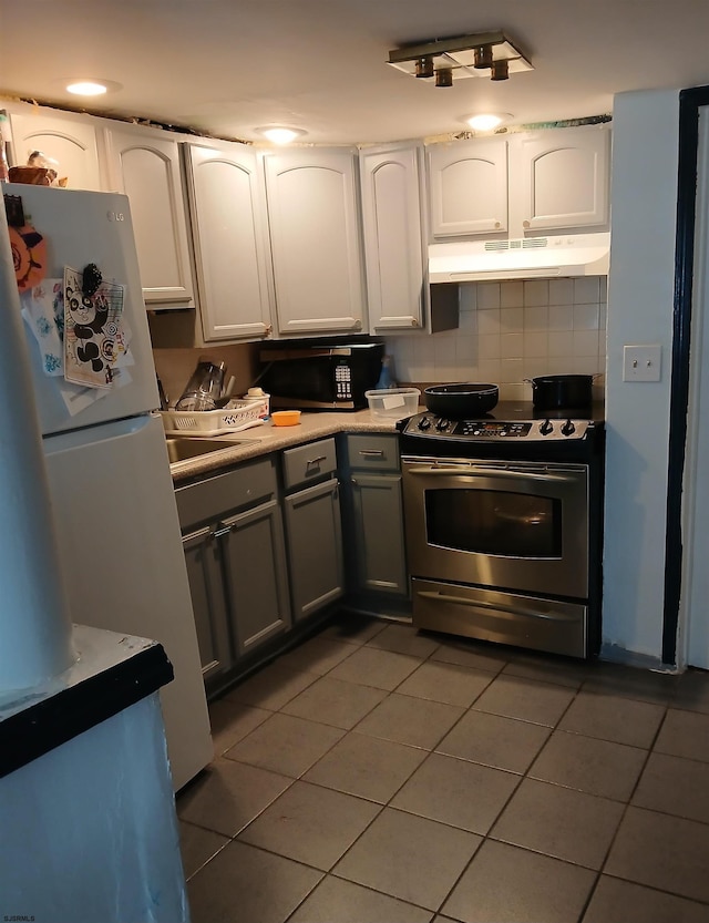 kitchen with white fridge, white cabinets, dark tile flooring, backsplash, and stainless steel range with electric stovetop