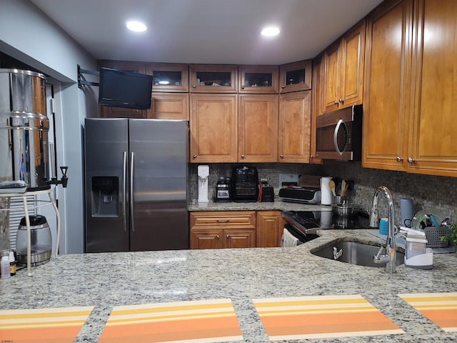 kitchen featuring backsplash, sink, stainless steel appliances, and light stone counters