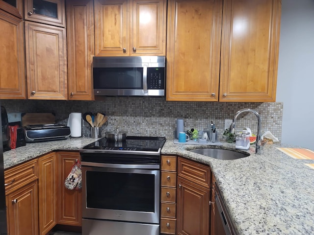 kitchen with sink, appliances with stainless steel finishes, tasteful backsplash, and light stone counters