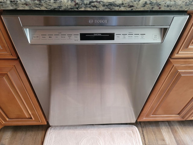 details with light hardwood / wood-style flooring and stainless steel dishwasher