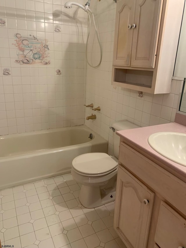 full bathroom featuring tile walls, tiled shower / bath, tile floors, toilet, and vanity