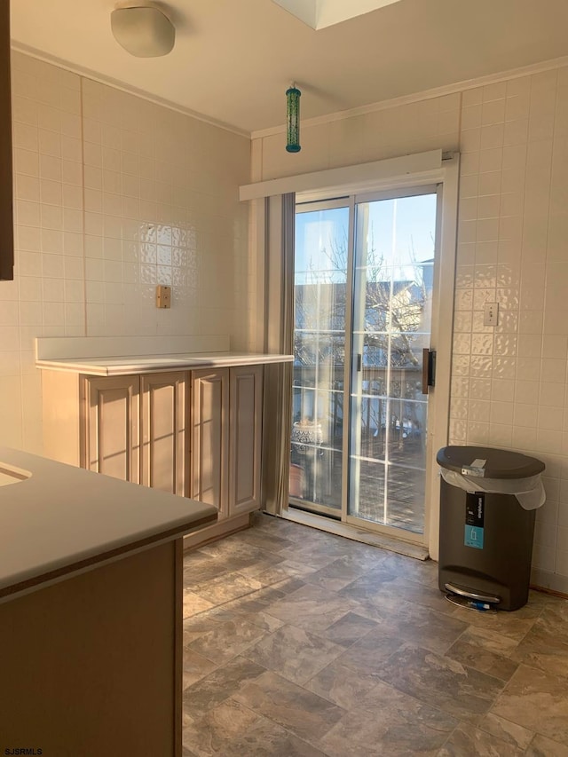 kitchen featuring dark tile flooring, tile walls, and crown molding