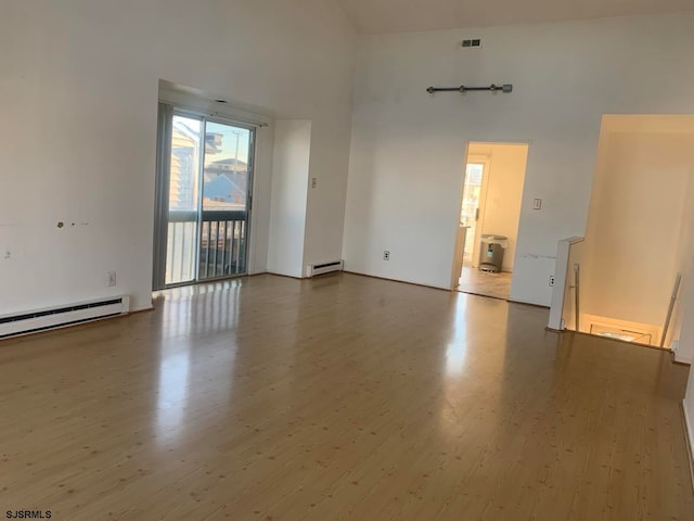 spare room with high vaulted ceiling, a baseboard radiator, and wood-type flooring