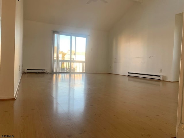 empty room featuring vaulted ceiling, hardwood / wood-style floors, and a baseboard heating unit