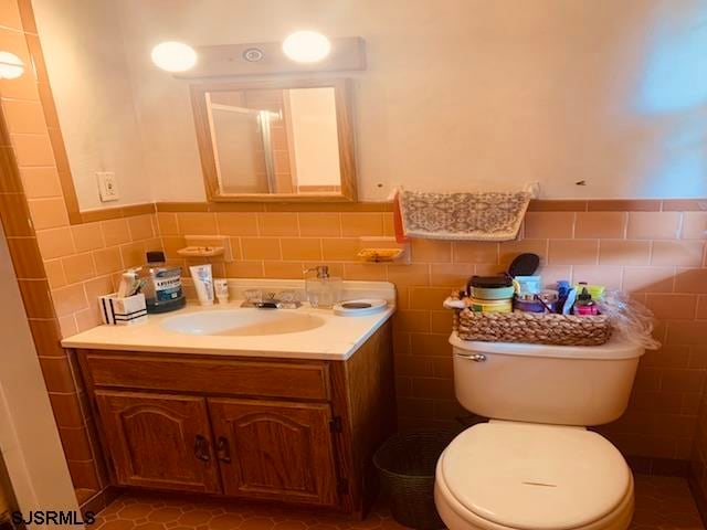 bathroom featuring tile flooring, vanity with extensive cabinet space, backsplash, and tile walls