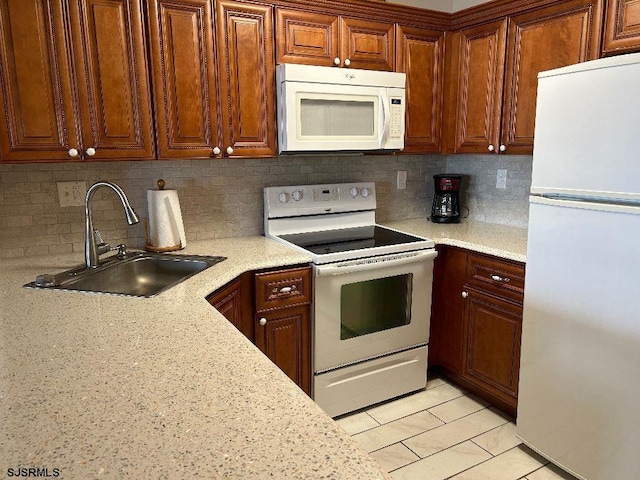 kitchen with tasteful backsplash, light stone countertops, sink, and white appliances