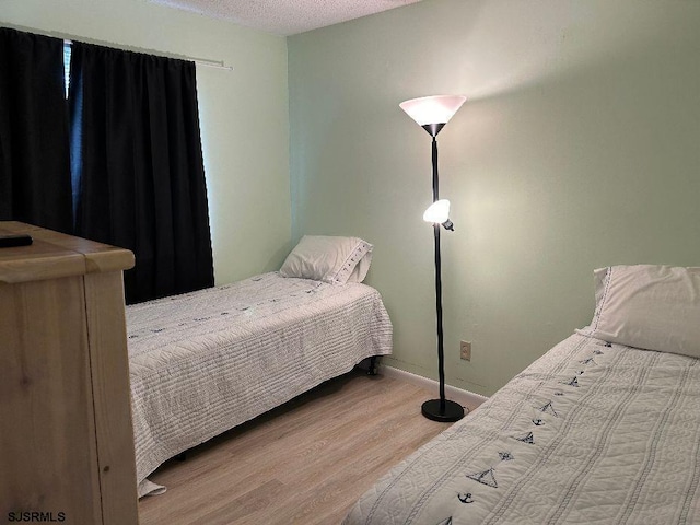 bedroom with a textured ceiling and light hardwood / wood-style floors