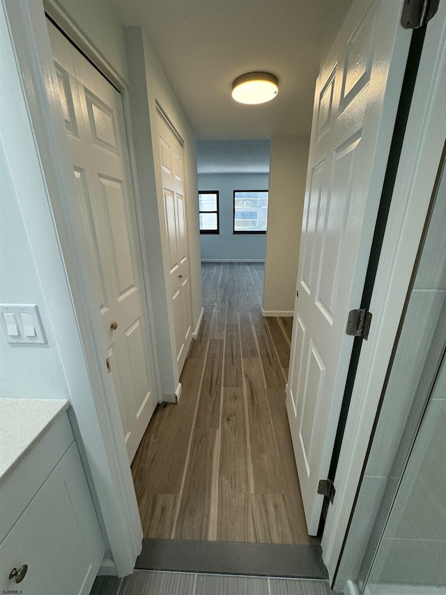 hallway featuring dark wood-style floors and baseboards