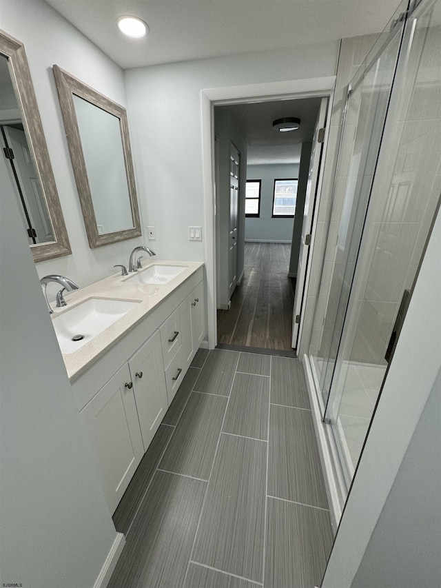 full bathroom featuring double vanity, a shower stall, and a sink