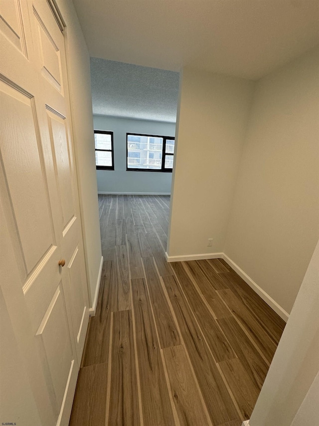 corridor with baseboards and dark wood-style flooring