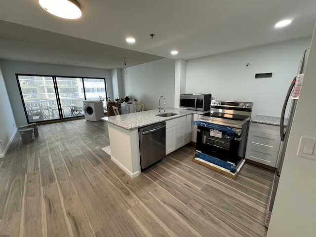 kitchen with light stone counters, open floor plan, stainless steel appliances, and wood finished floors