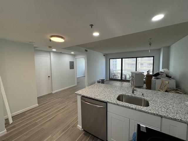 kitchen featuring open floor plan, dishwasher, light wood-type flooring, light stone counters, and a sink