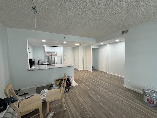 living room with wood finished floors, baseboards, visible vents, recessed lighting, and a textured ceiling