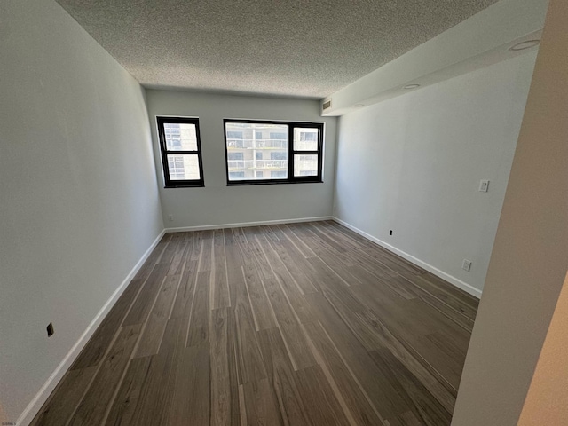 unfurnished room featuring dark wood-type flooring, baseboards, and a textured ceiling