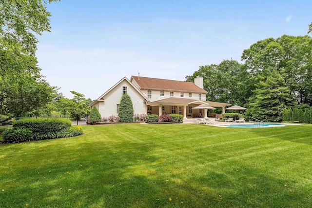 rear view of house with a fenced in pool, a yard, and a patio