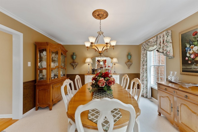 dining area featuring light carpet, ornamental molding, and an inviting chandelier