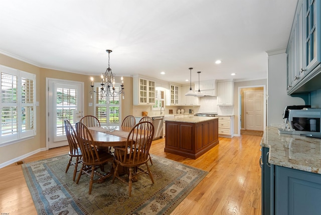 dining room with a notable chandelier, sink, light wood-type flooring, and crown molding