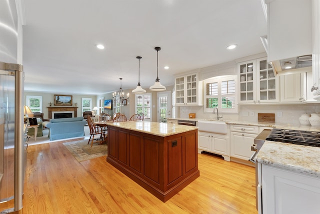 kitchen with sink, white cabinets, custom range hood, and a kitchen island