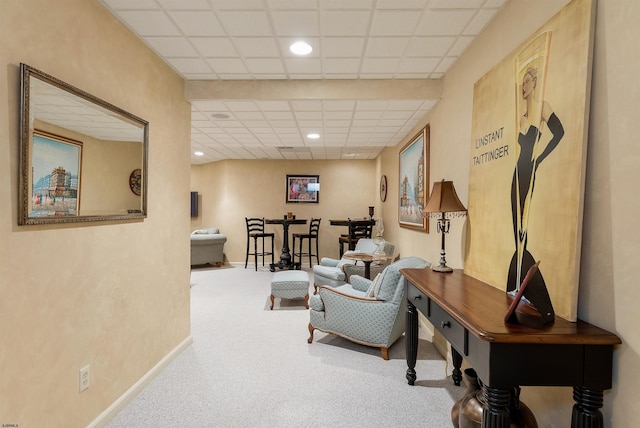 sitting room featuring a drop ceiling and carpet floors