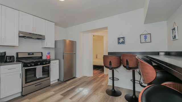 kitchen featuring backsplash, white cabinetry, light hardwood / wood-style flooring, and appliances with stainless steel finishes