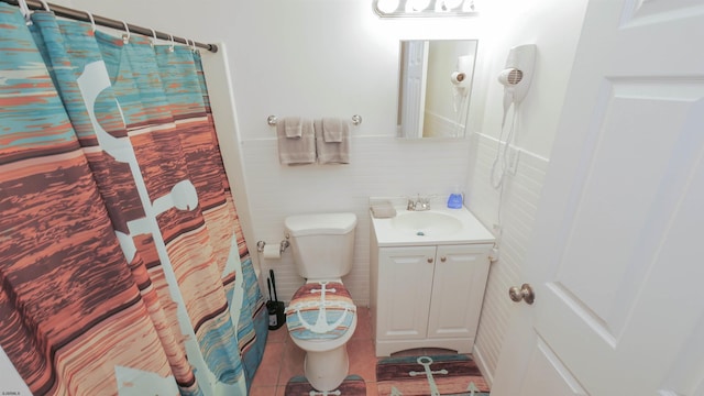 bathroom featuring tile patterned floors, vanity, toilet, and tile walls