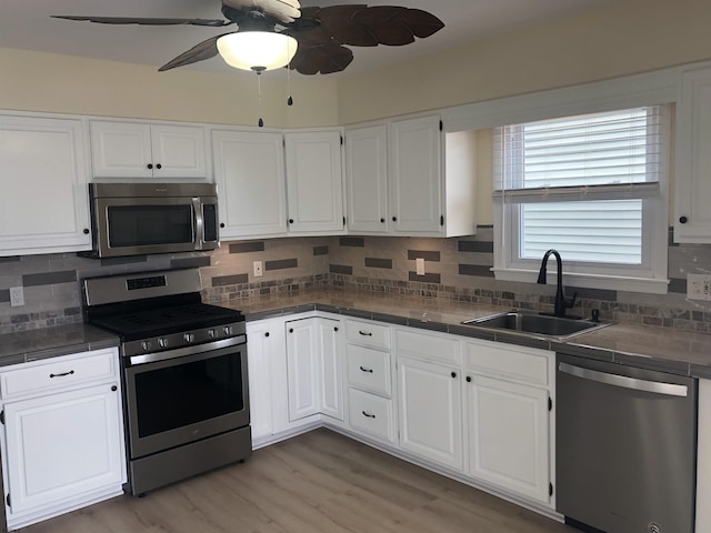 kitchen with white cabinets, sink, ceiling fan, decorative backsplash, and appliances with stainless steel finishes