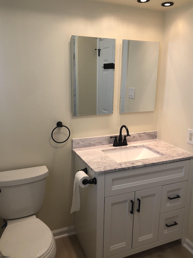 bathroom with hardwood / wood-style floors, vanity, and toilet