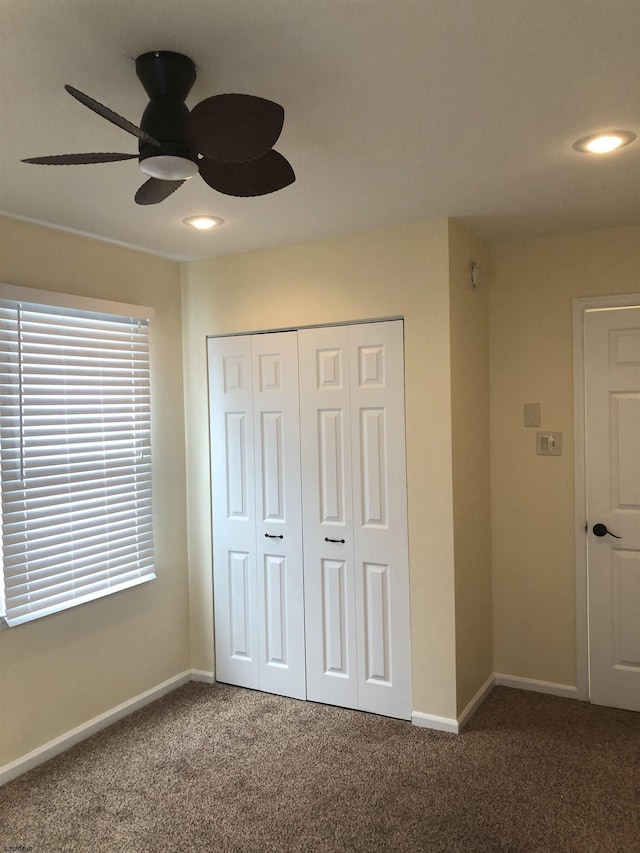 unfurnished bedroom featuring dark colored carpet, ceiling fan, and a closet