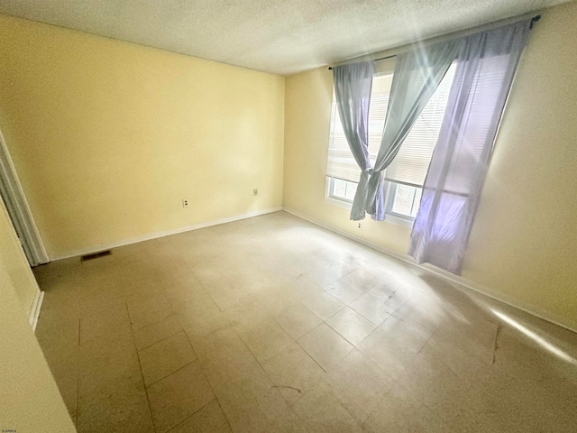 tiled empty room with a textured ceiling