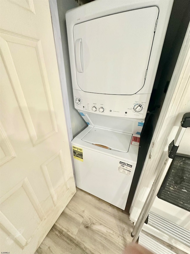 clothes washing area with stacked washing maching and dryer and light hardwood / wood-style flooring