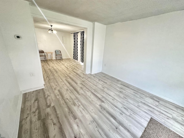 unfurnished living room featuring a textured ceiling, an inviting chandelier, and hardwood / wood-style floors