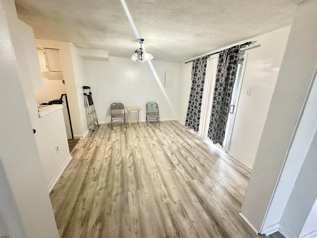 unfurnished dining area with a notable chandelier, a textured ceiling, and hardwood / wood-style floors