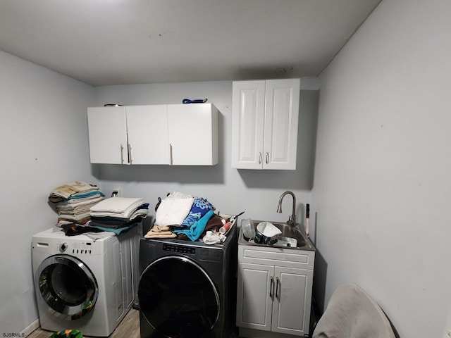 clothes washing area featuring cabinet space, a sink, and separate washer and dryer