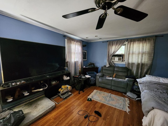 living area featuring cooling unit, ornamental molding, ceiling fan, and wood finished floors