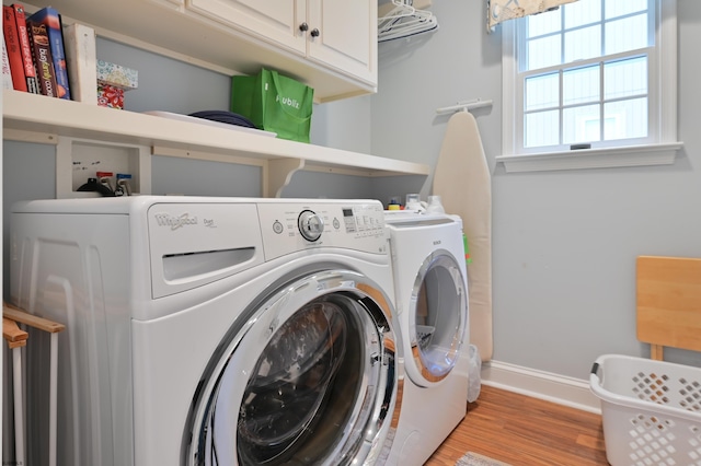 laundry room featuring cabinets, light wood-type flooring, and washing machine and clothes dryer