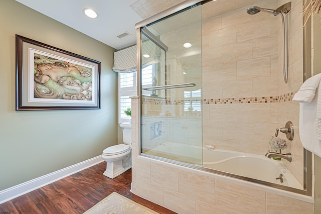 bathroom featuring toilet, hardwood / wood-style floors, and combined bath / shower with glass door