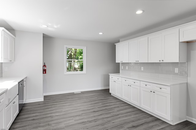 kitchen with white cabinets, hardwood / wood-style floors, backsplash, and stainless steel dishwasher