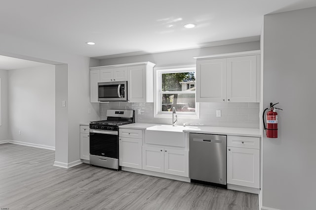 kitchen with stainless steel appliances, white cabinetry, and sink