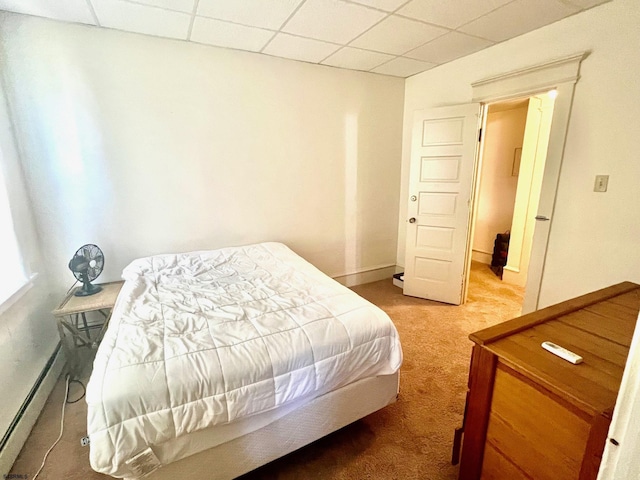 carpeted bedroom with a drop ceiling and a baseboard heating unit