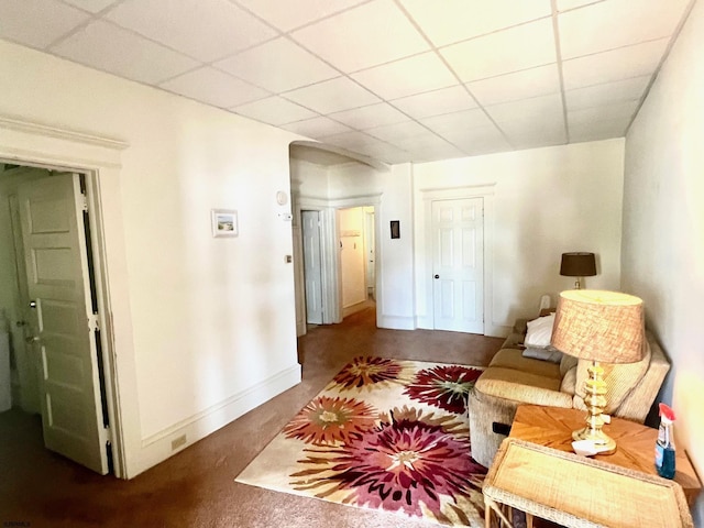 living area featuring carpet flooring and a drop ceiling