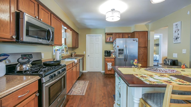 kitchen with sink, appliances with stainless steel finishes, and dark hardwood / wood-style flooring