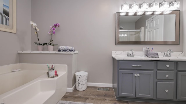 bathroom featuring a tub, hardwood / wood-style floors, and dual bowl vanity