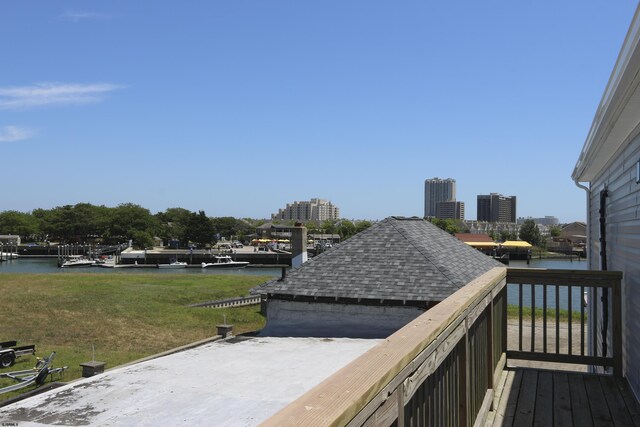 wooden deck with a water view and a lawn