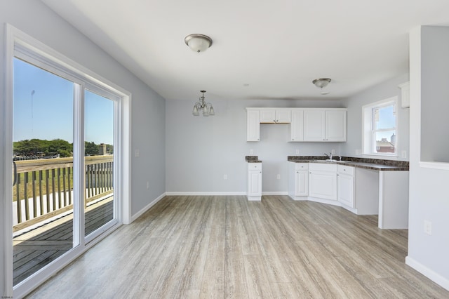 kitchen with white cabinetry, hanging light fixtures, light hardwood / wood-style floors, and a notable chandelier